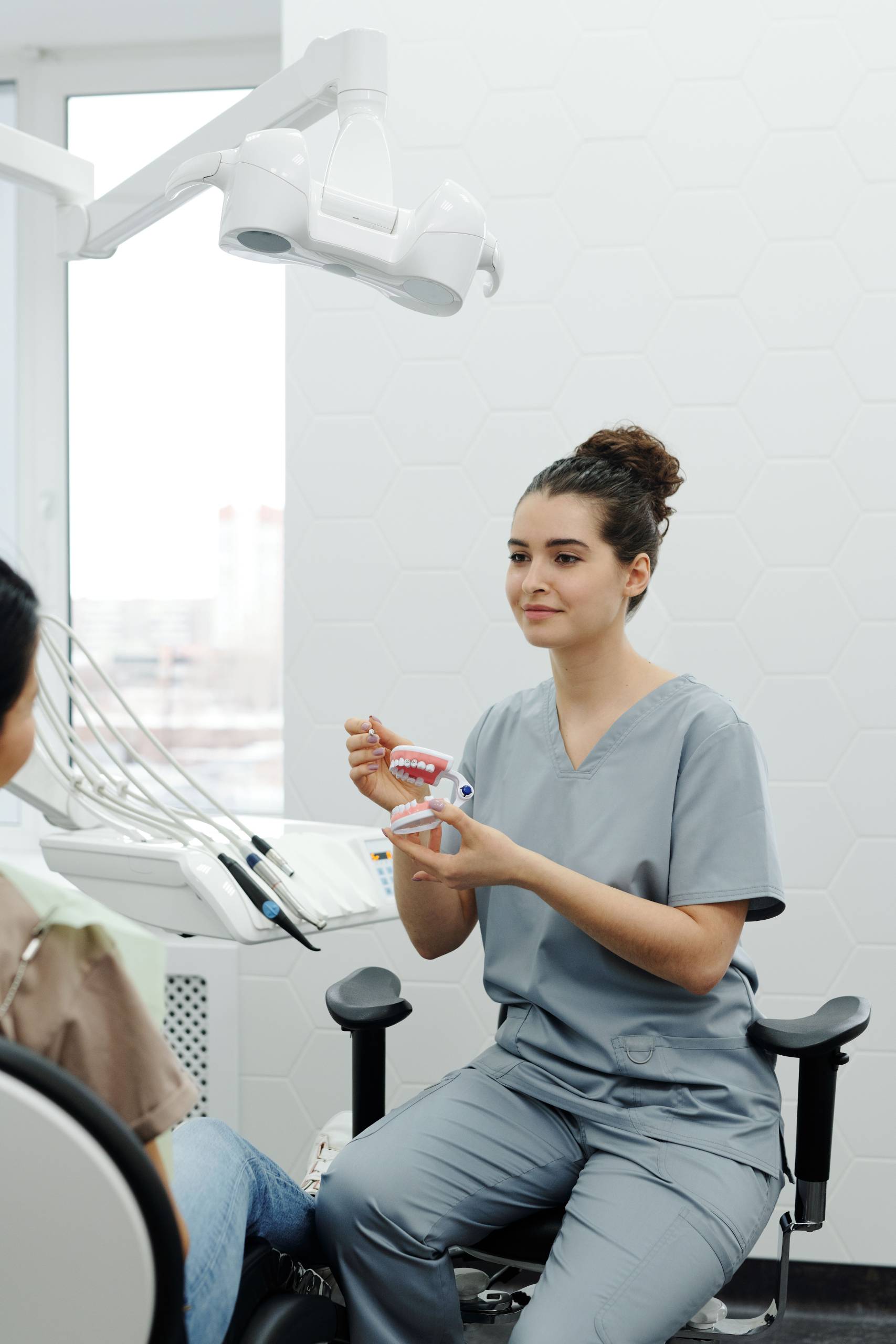 Dental professional using a model of teeth with braces to explain orthodontic treatment to a seated patient