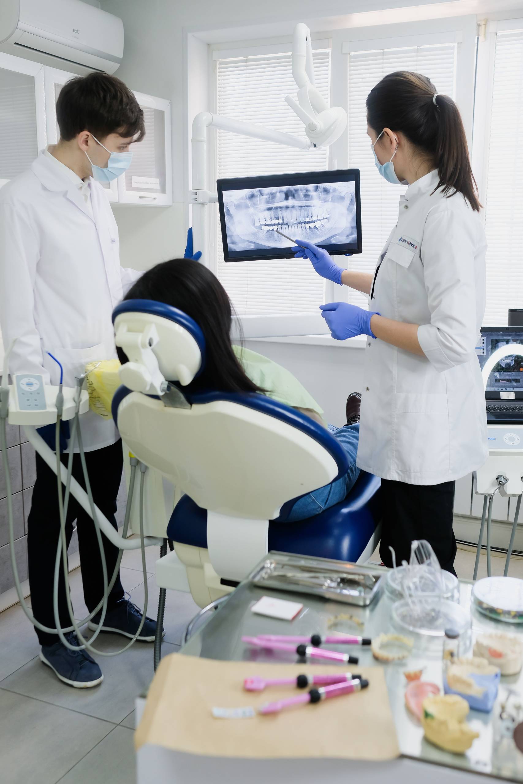 Two dental professionals reviewing a patient's panoramic X-ray on a monitor during a consultation