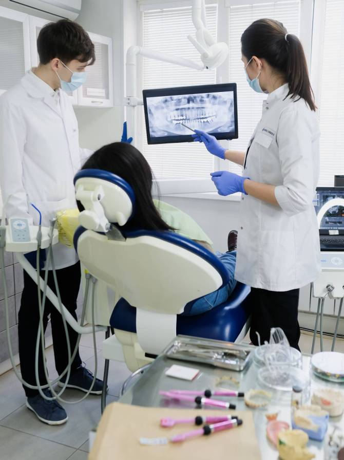 Two dental professionals reviewing a patient's panoramic X-ray on a monitor during a consultation